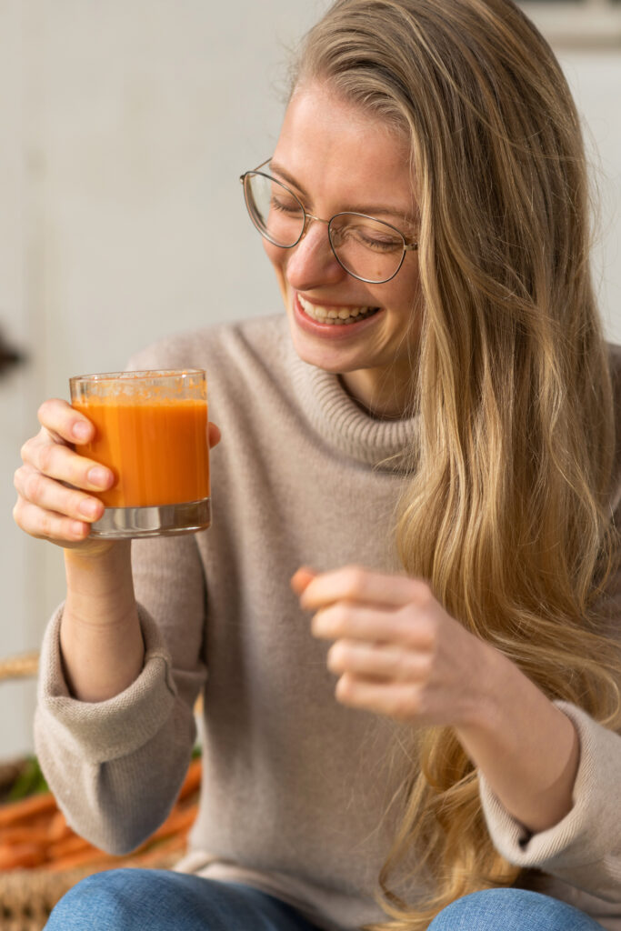 Model Tessa hält ein Glas mit Karottensaft