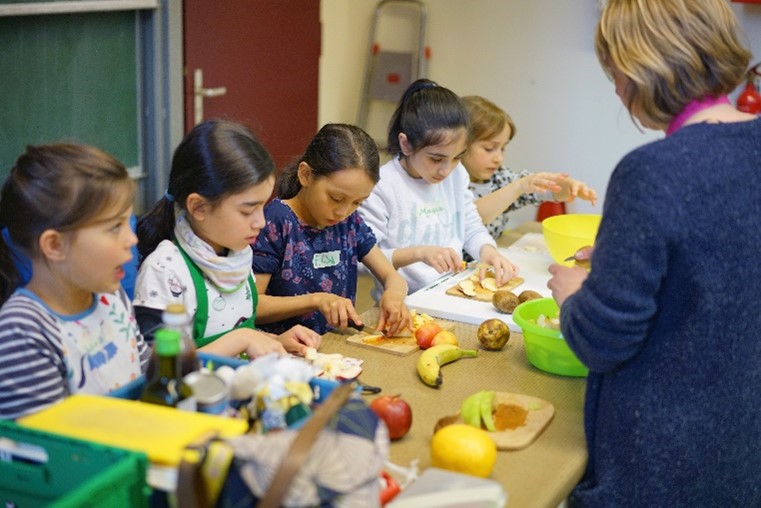 Unser Engagement für mehr Lebensmittelwertschätzung: Bei einer Veranstaltung von Restlos Glücklich schnippeln Kinder Obst und Gemüse.